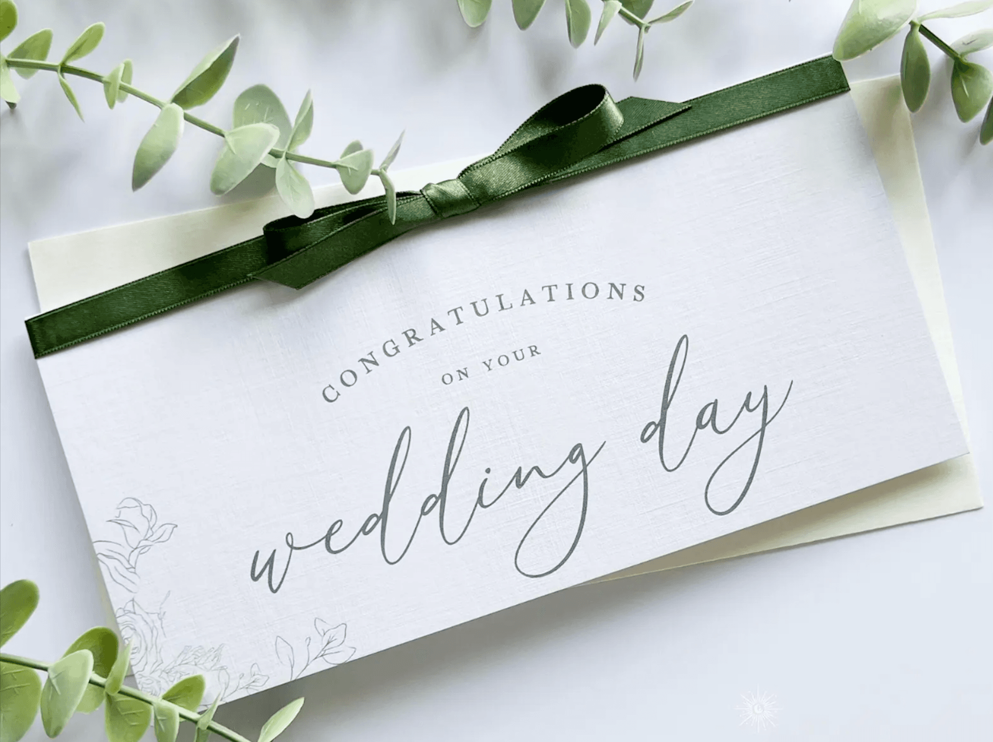 A ‘congratulations on your wedding day’ card tied with a green ribbon and eucalyptus